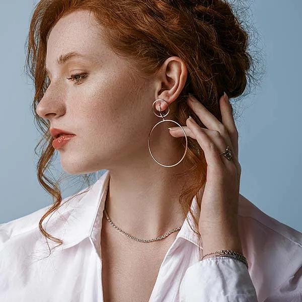 Schöne, elegante, sommersprossige rothaarige Frau mit luxuriösem Silberschmuck: Ohrringe, Kette, posiert im Studio, auf blauem Hintergrund. Konzeption der Schmuckwerbung. Nahaufnahme eines Profilporträts.